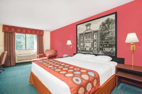 ein Hotelzimmer mit einem großen Bett und einer roten Wand in der Unterkunft Super 8 by Wyndham Gettysburg in Gettysburg