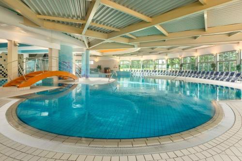 ein großer Pool mit blauem Wasser in einem Gebäude in der Unterkunft Ramada Resort Kranjska Gora in Kranjska Gora