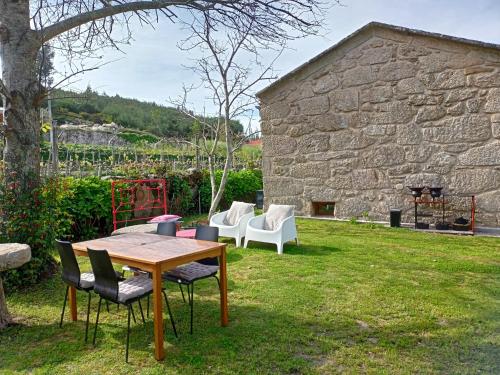 a table and chairs in a yard next to a stone building at Jardim da Rosa in Monção