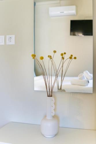 a white vase with flowers in it in front of a mirror at Fedra Plakias Apartments in Plakias