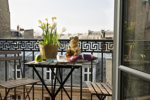 a teddy bear sitting on a table on a balcony at Hotel Le Petit Chomel in Paris