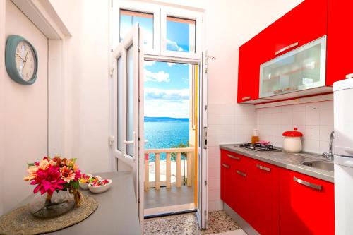 cocina con armarios rojos y vistas al océano en Beach House Lemonade, en Jesenice