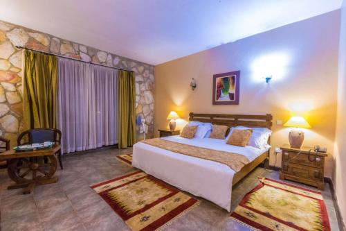 Un dormitorio con una cama grande y una pared de piedra. en Mountains of the Moon Hotel Fort Portal, en Fort Portal