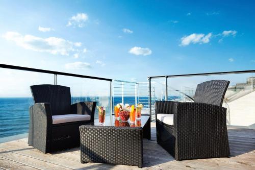 dwa krzesła i stół na tarasie z oceanem w obiekcie Boulevard Ustronie Morskie by Zdrojowa w mieście Ustronie Morskie