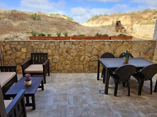 a patio with tables and chairs and a stone wall at Sanchis Guarner Bajo Solo Familias Serviplaya in Playa de Xeraco