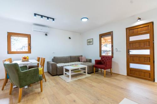 Una sala de estar con un sofá, una mesa y sillas. en Apartmani Vajati Gradac, en Valjevo