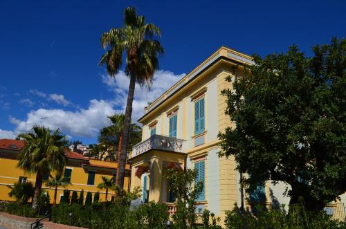 een geel huis met een palmboom ervoor bij Alaxia Luxury Apartments in Alassio