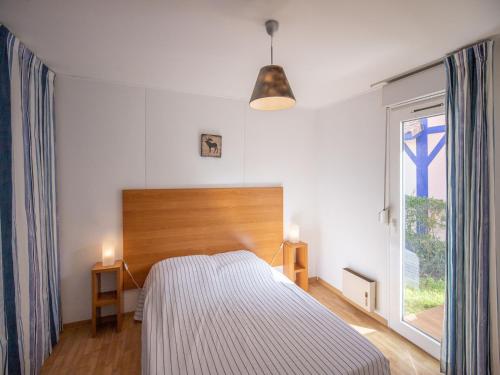 a bedroom with a bed and a large window at Vacancéole - les villas du lac in Soustons