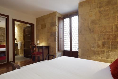 a bedroom with a white bed and a stone wall at Saiaz Getaria Hotela in Getaria