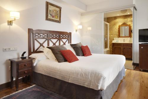a bedroom with a large bed and a bathroom at Saiaz Getaria Hotela in Getaria