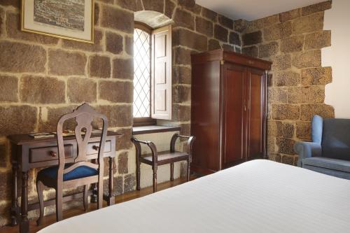 a bedroom with a bed and a desk and chairs at Saiaz Getaria Hotela in Getaria