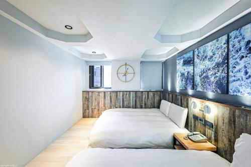 a bedroom with two beds and a clock on the wall at 亞馨文旅 近東大門夜市 有免費停車場 可自助入住 in Hualien City