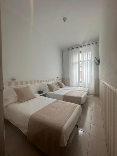 three beds in a room with white walls at Hotel Torino in El Masnou