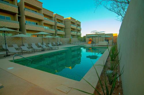 a swimming pool with chairs and umbrellas next to a building at Evamar San Carlos in San Carlos