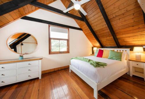 een slaapkamer met een wit bed en een spiegel bij Willunga Cottage- Sleeps 6 Pool in Willunga