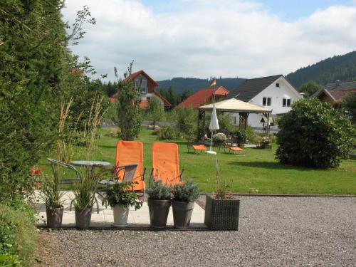 zwei orangefarbene Stühle und Pflanzen in einem Hof in der Unterkunft Haus Schwedes in Titisee-Neustadt