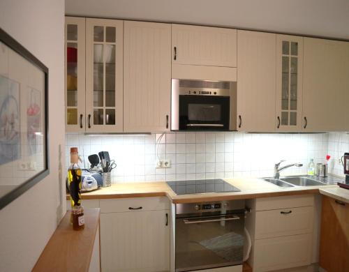 a kitchen with white cabinets and a sink and a microwave at Haus Schwedes in Titisee-Neustadt