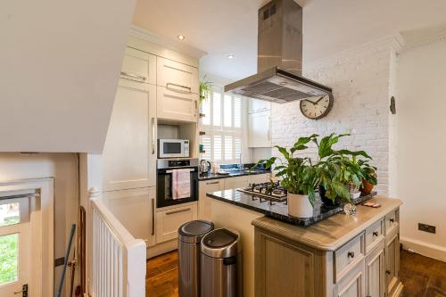 a kitchen with white cabinets and a clock on the wall at Historic 18th Century Terrace House in London