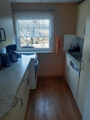 a kitchen with white cabinets and a window and a sink at Bed and Breakfast 4 in Korswandt