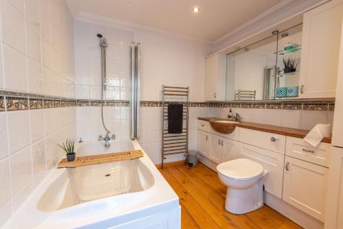 a bathroom with a tub and a toilet and a sink at Dudley House in Woolacombe