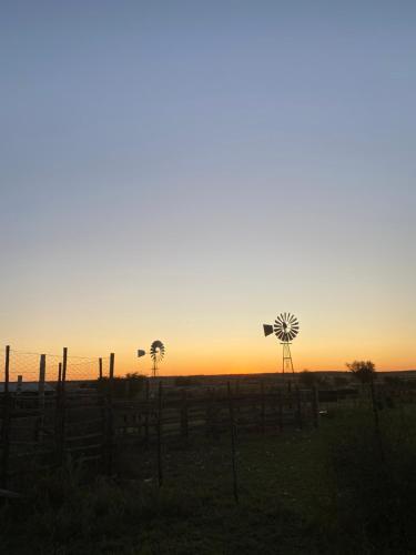 ein Sonnenuntergang mit zwei Windmühlen auf einem Feld in der Unterkunft Wiida Gasteplaas in Hopetown