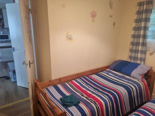 a small bedroom with a bed with a striped blanket at Beautiful 2-Bed Villa in Camelford in Camelford