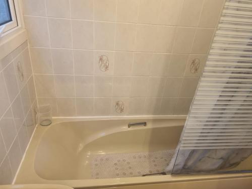 a white bath tub in a white tiled bathroom at Beautiful 2-Bed Villa in Camelford in Camelford