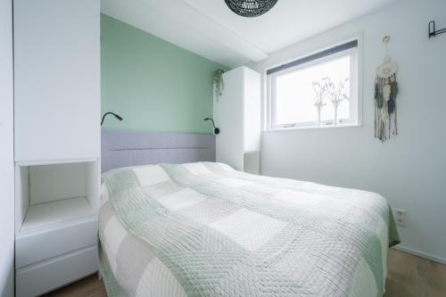 a white bedroom with a bed and a window at Vakantiehuis De Zeearend Dishoek in Dishoek
