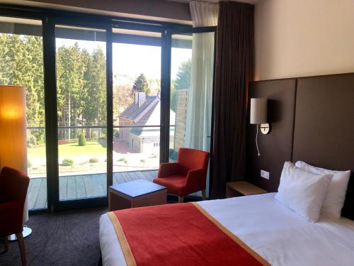 a hotel room with a bed and a large window at Hotel de la Source in Francorchamps