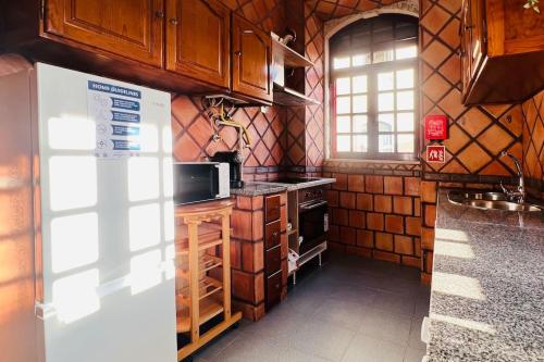 a kitchen with wooden cabinets and a refrigerator at Palacete da Serenata @ Sé Velha in Coimbra