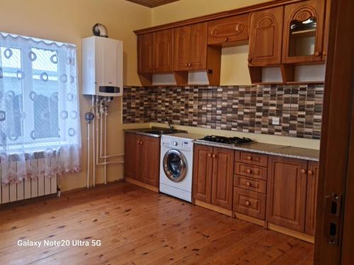 cocina con armarios de madera y lavadora en Rose House, en Sheki