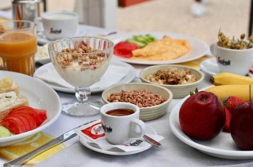 una mesa con platos de comida y tazas de café en Zea Apartments, en Himare