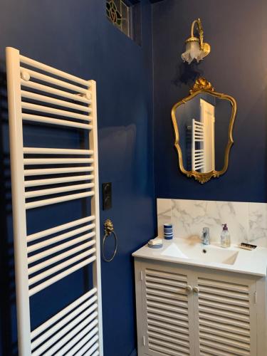 a blue bathroom with a sink and a mirror at La Maison du Magistrat in Durban-Corbières
