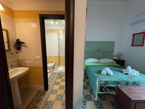 1 Schlafzimmer mit einem grünen Bett und einem Badezimmer in der Unterkunft Teatro del Sole Cavour in Palermo