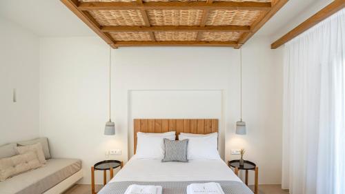 a bedroom with a white bed and a couch at Kalami Suites in Livadi