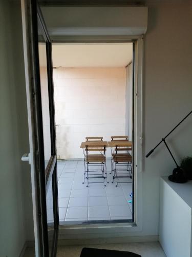 - une table et des chaises dans une pièce dotée d'une porte en verre dans l'établissement Studio meublé 30m2 avec terrasse, à Rouen