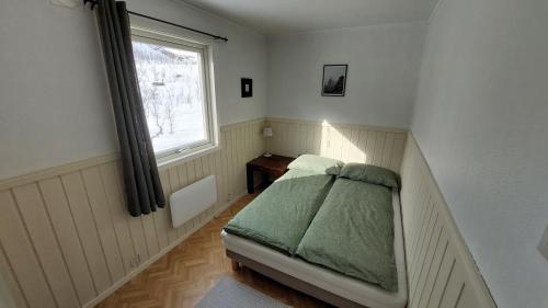 a small bedroom with a bed and a window at Holiday home on Senja in Grashopen