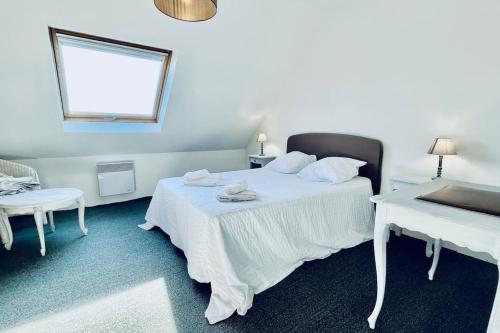 - une chambre avec un lit blanc, une table et une fenêtre dans l'établissement Les agapanthes - vue mer, à Roscanvel
