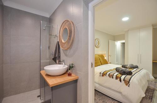 ein Bad mit einem Waschbecken, einem Bett und einem Spiegel in der Unterkunft Maki-Saki Boutique Self-Catering Accommodation in Yzerfontein