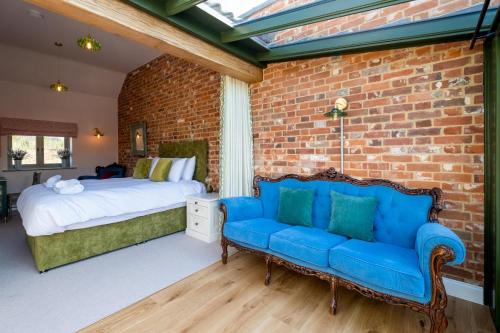 a bedroom with a blue couch and a brick wall at Alde Bay Farm - Barn Owl Sanctuary in Aldeburgh