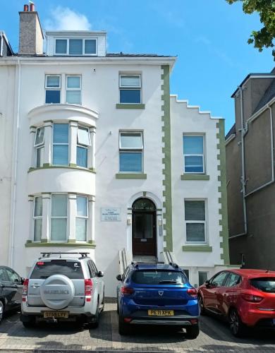 two cars parked in front of a white house at Lovely one bedroom apartment in Llandudno