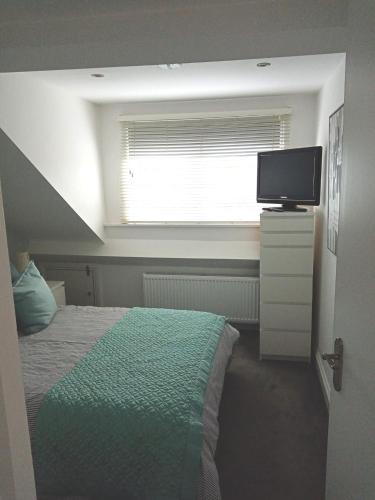 a bedroom with a bed and a window with a television at Lovely one bedroom apartment in Llandudno