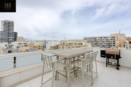una mesa y sillas en un balcón con parrilla en Stylish 1BR Penthouse w Panoramic Views & BBQ by 360 Estates, en Il-Gżira