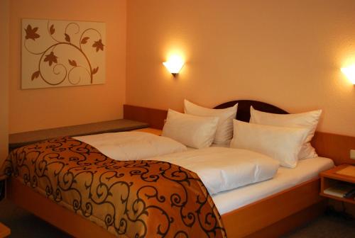 a hotel room with a bed with white pillows at Im Winkel Appartements und Zimmer in Langenargen