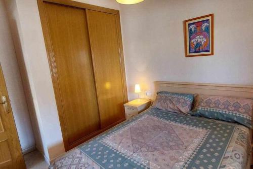 ein kleines Schlafzimmer mit einem Bett und einem Holzschrank in der Unterkunft Apartamento Salamanca 4 in Santa Pola