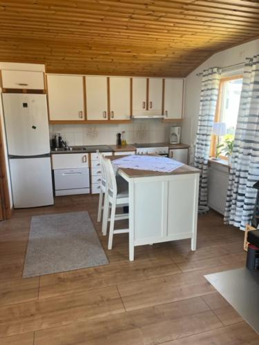 a kitchen with white cabinets and a table and chairs at Stuga med havsutsikt i Falkenberg in Falkenberg