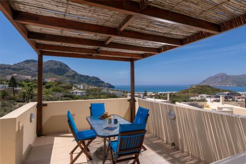 einen Tisch und Stühle auf einem Balkon mit Meerblick in der Unterkunft Plakias Panorama Homes in Plakias