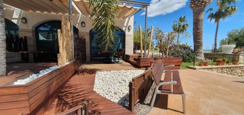 a porch of a house with a bench and palm trees at Miami Mar - Boutique Hotel & Restaurante in Sant Carles de la Ràpita