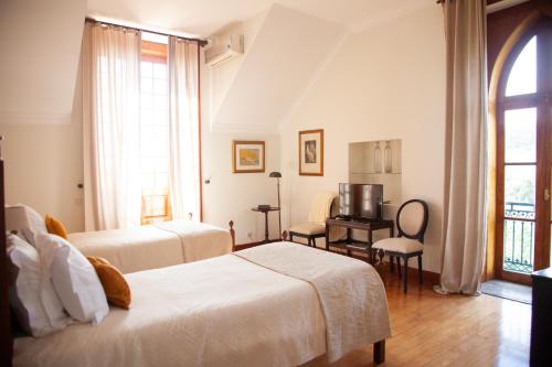 a bedroom with two beds and a desk with a television at Quinta da Nasce Água in Angra do Heroísmo