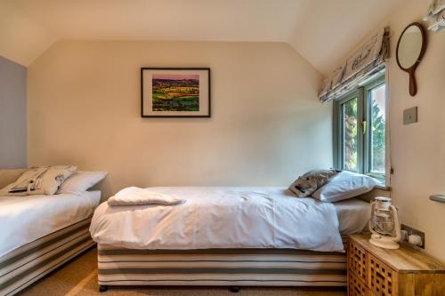 a bedroom with two beds and a window at Ottery St Mary Cottages in Ottery Saint Mary